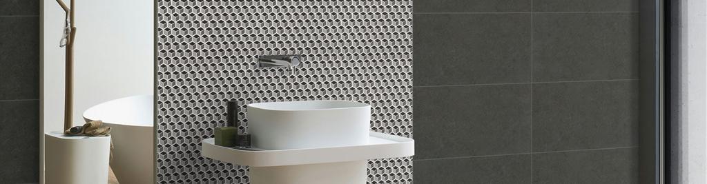 Lavabo moderno con pared de mosaico hexagonal en tonos grises.